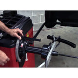 Tire balancing machine being operated by hands adjusting its components.