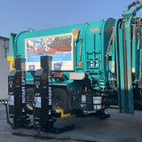 Turquoise garbage truck with hydraulic lifting mechanisms.