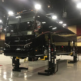 Sleek black luxury RV or motorhome elevated on hydraulic lifts.