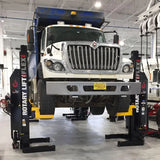 Heavy-duty truck elevated on a vehicle lift in a maintenance garage.