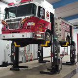 Fire truck elevated on hydraulic lifts in a maintenance bay.