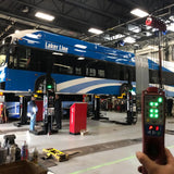 Blue and white ’Laker Line’ bus elevated on maintenance lifts in a garage.