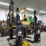 Forklift elevated on hydraulic lifts in a repair or maintenance setting.