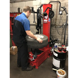 Tire changing machine being operated by a mechanic.